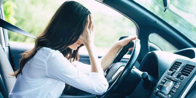 Frau im Auto mit Kopfschmerzen - Elektrosmog im Auto