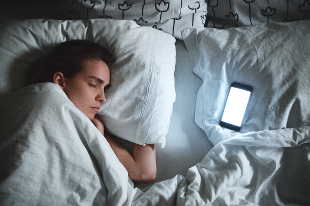 Frau im Bett mit aktivem Handy